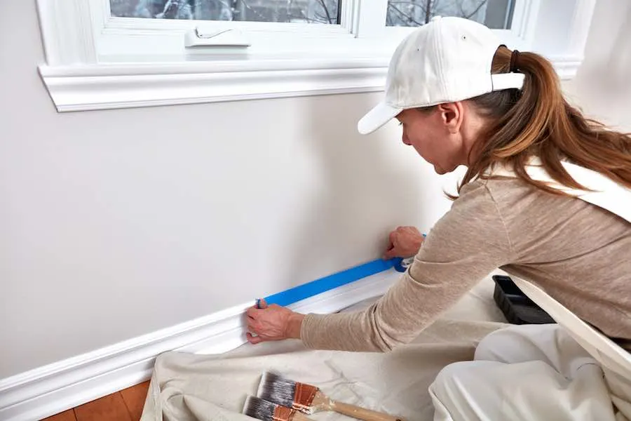The Best Painters Tape For Every Surface 2 Woman applying painter's tape