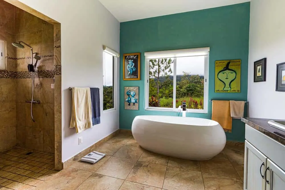 22 Inspiring Bathroom Paint Colors 3 A bathroom with a green wall and window open to a verdant forest.