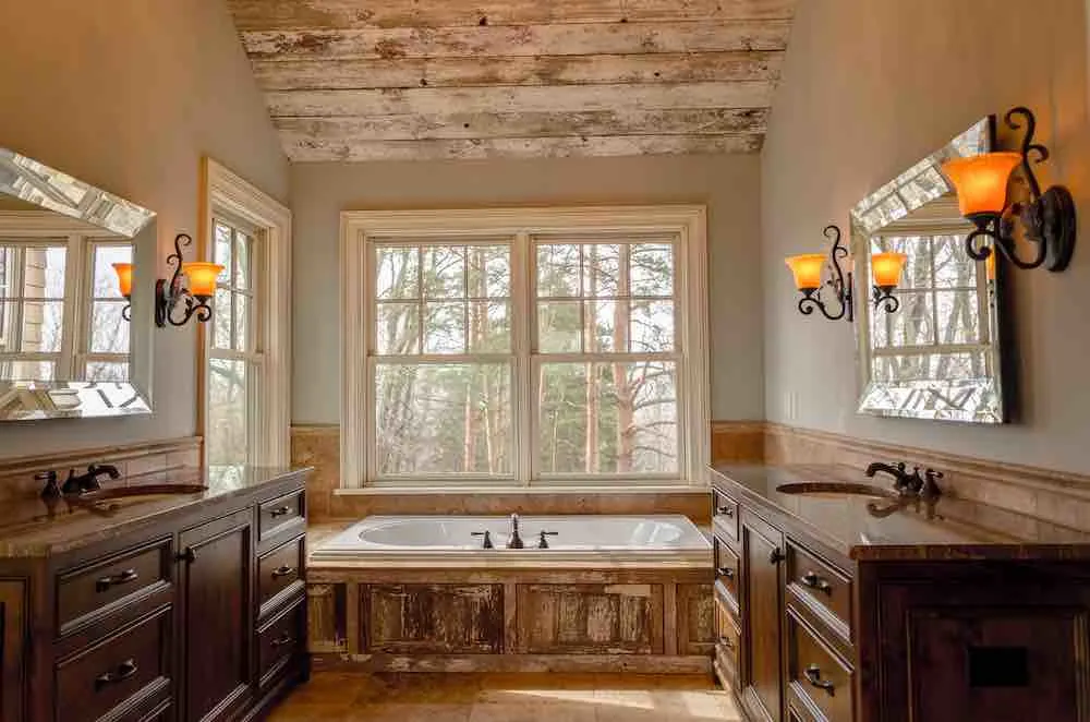 22 Inspiring Bathroom Paint Colors 7 A bathroom with lots of natural light, and evergreen trees outside the window. It has wood accents and dark beige paint.