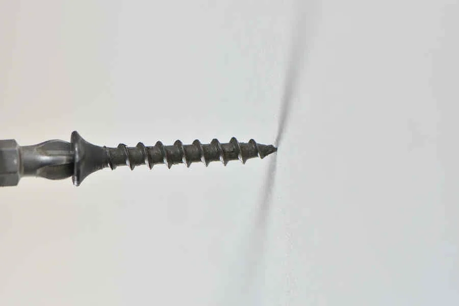 Ultimate Guide to Drywall Screws 2 Close up of installing a black spiral threaded sheetrock or drywall screw with a crosspoint head
