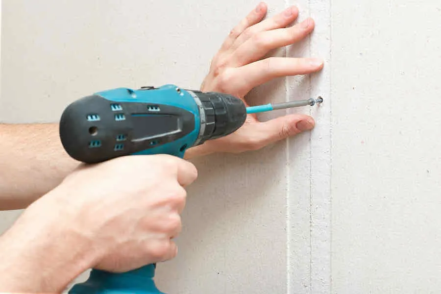 Drywall Nails vs Screws: Which Is Best? 2 person fastens drywall nails with a screwdriver
