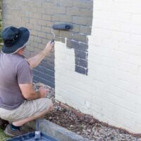 A man painting with the best paint for exterior brick