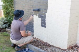 A man painting with the best paint for exterior brick
