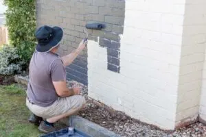 A man painting with the best paint for exterior brick