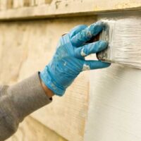 A painter applying the best exterior primer to a wooden home exterior