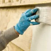 A painter applying the best exterior primer to a wooden home exterior