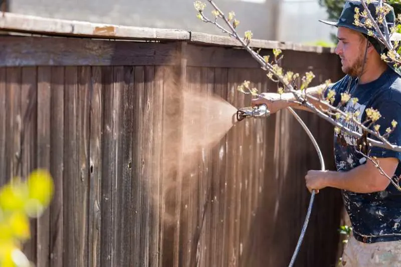 Best Paint Sprayer for Exterior House Painting Projects: My Top 8 Picks 4 a man painting a fence with an airless paint sprayer