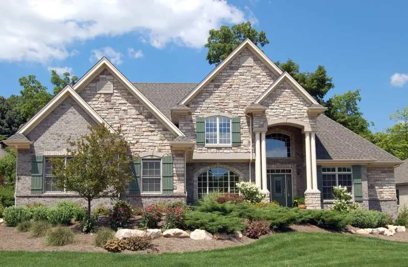 The 7 Pros and Cons of Painting Exterior Brick 5 A brick house with landscaping