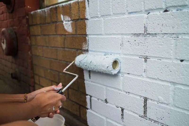 The Best Paint For Exterior Brick 4 A woman painting exterior brick