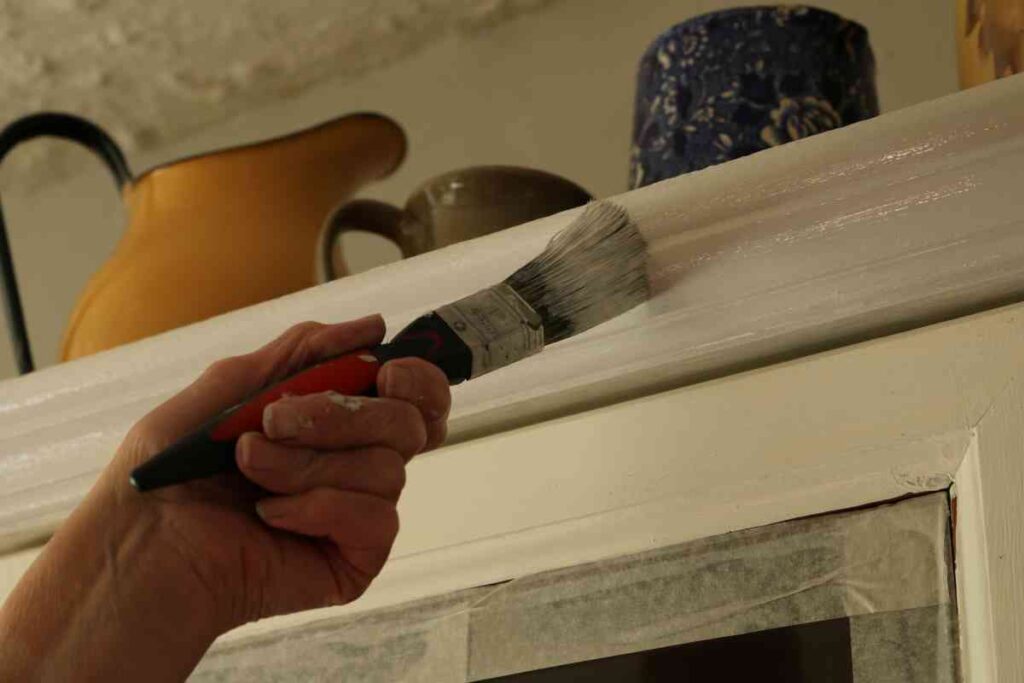 Woman painting kitchen cupboard cabinets white