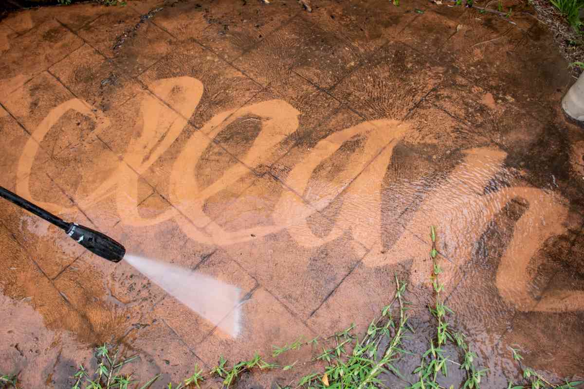 How to power wash a driveway by spraying the word CLEAN into the grime