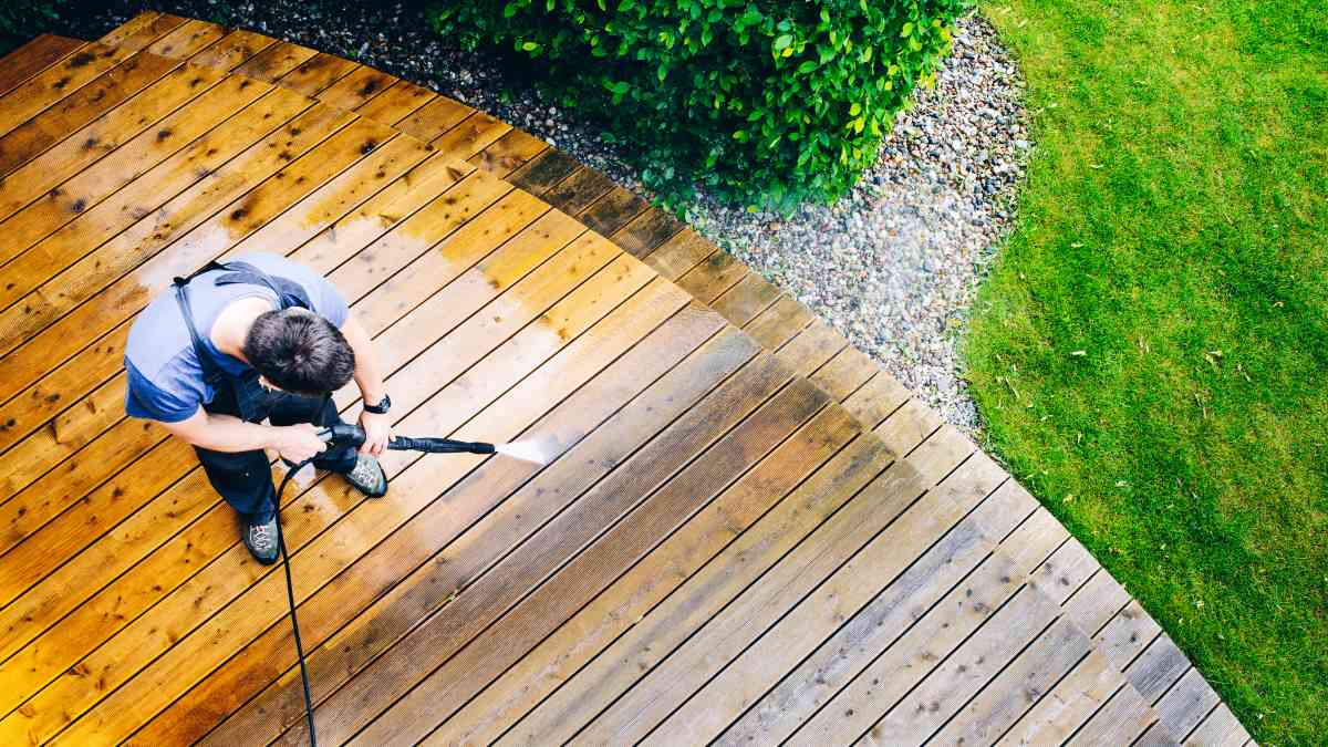 A man showing how to power wash a deck