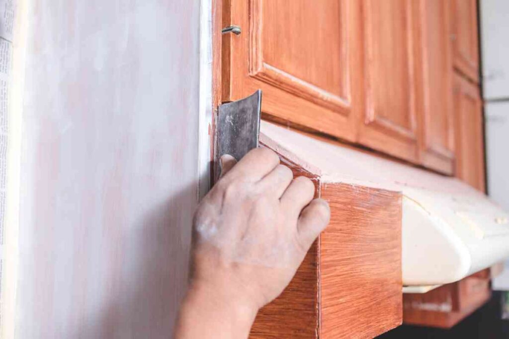 A man sanding kitchen cabinets prior to painting