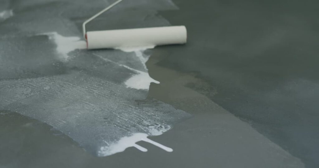 Rolling sealer onto a concrete floor.