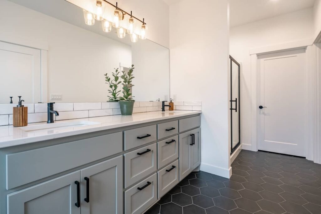 Light gray bathroom vanity cabinets with white solid surface countertop.