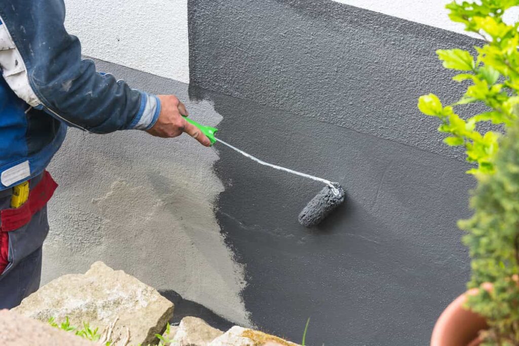 Rolling gray paint onto a primed concrete wall.