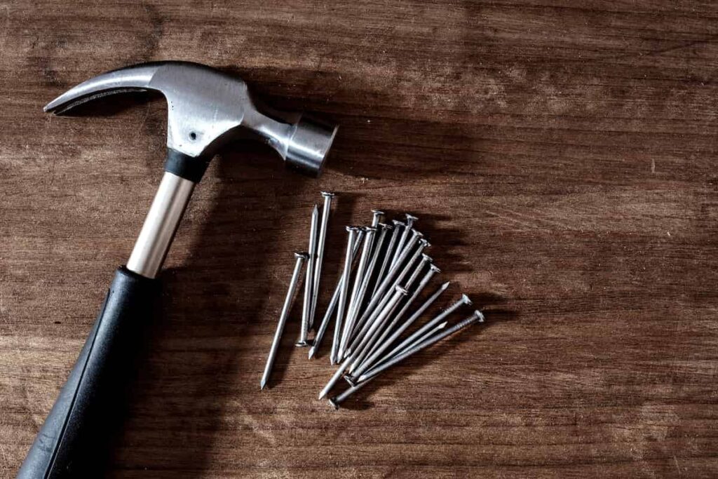 24 DIY Home Improvement Tools Every Homeowner Should Have 6 A claw hammer and nails on a table.