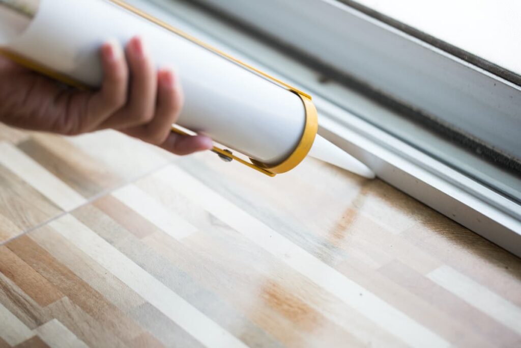 24 DIY Home Improvement Tools Every Homeowner Should Have 8 Using a caulk gun to lay sealant around a door.