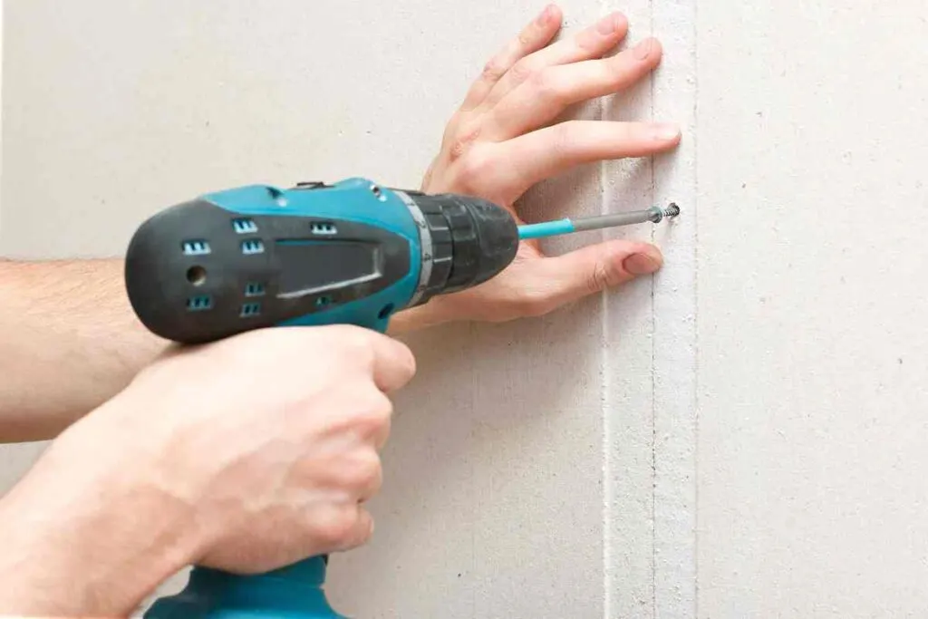 How to Repair Drywall: From Holes to Perfect Walls 3 Close up of a man using a drill to secure drywall with drywall screws