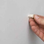 A man's hand showing how to remove drywall anchors