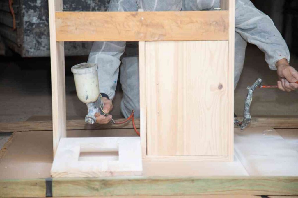 Using a paintgun to spray paint cabinets

