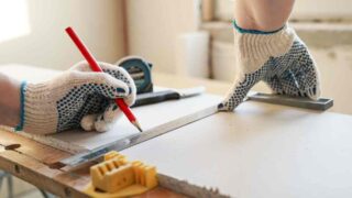 Using a straight edge to measure and cut a large piece of drywall