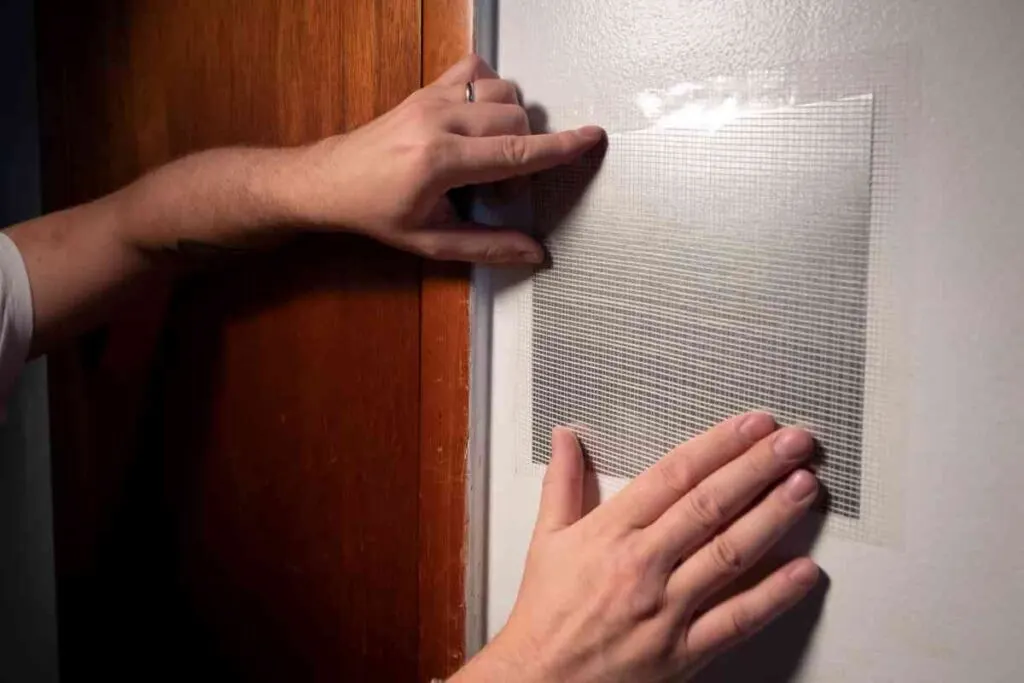 How to Repair Holes in Drywall: Step-by-Step Instructions 1 A man's hands showing how to repair holes in drywall