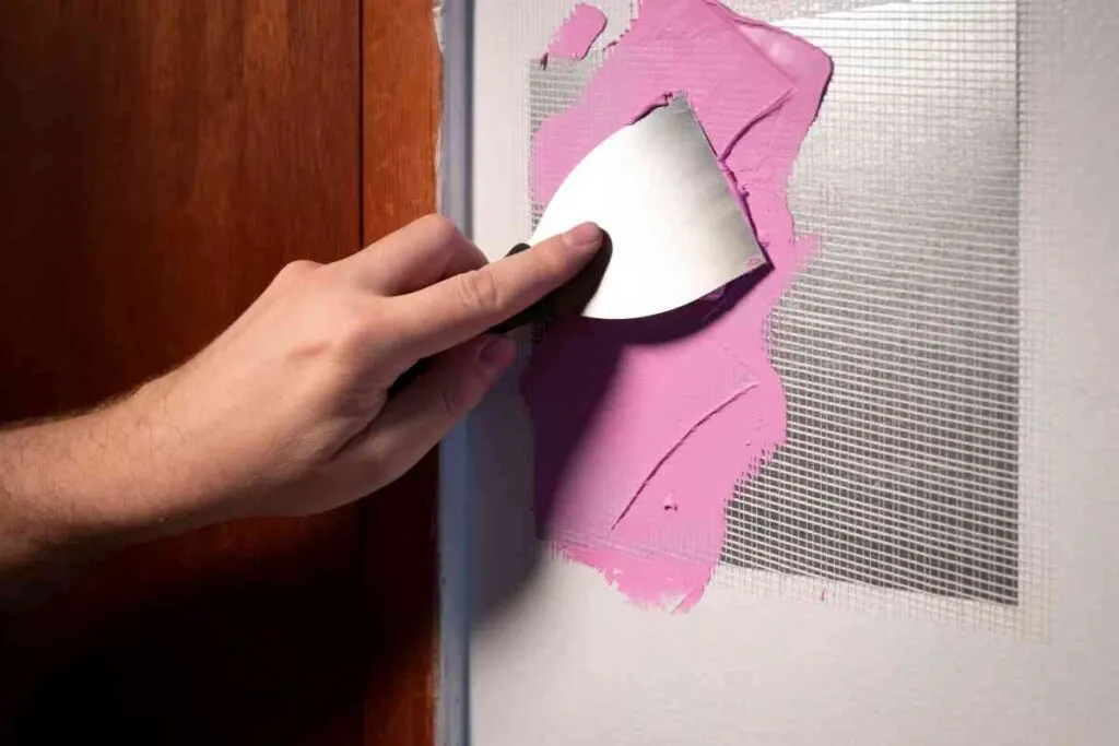 How to Repair Holes in Drywall: Step-by-Step Instructions 2 Man using a drywall patch kit to repair a hole in drywall
