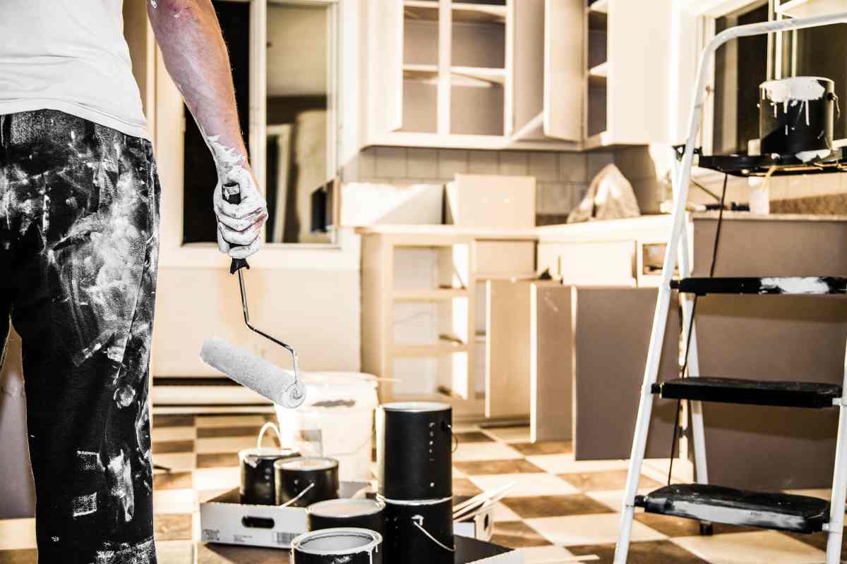 A man looking at the mess he's made painting his kitchen and wondering about hiring someone for professional kitchen cabinet painting