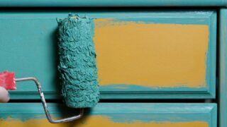 Someone painting furniture with a roller. Learn how to paint furniture like a pro!