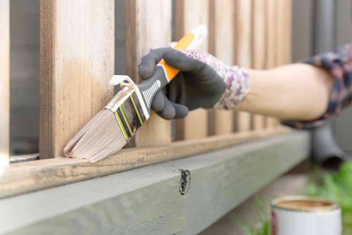 Woman in long sleeves using the best cold weather paint to paint her porch