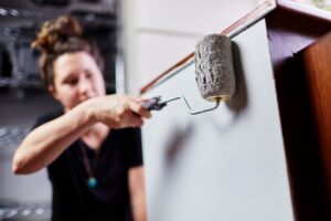 Woman using a roller for painting cabinets in a bathroom