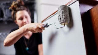 Woman using a roller for painting cabinets in a bathroom