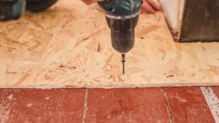 Person using a drill to install screws when replacing bathroom subfloor