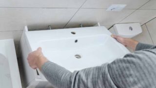 A person attaching a new bathroom sink to the wall